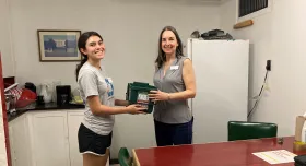 A Resource Recovery student intern hands a composting bin to a UT staff member.