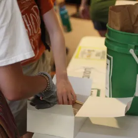 Volunteers help incoming students sort their lunch remains: unopened, compost, recycle.